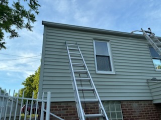 Ladders set up against a two-story home for a seamless gutter installation